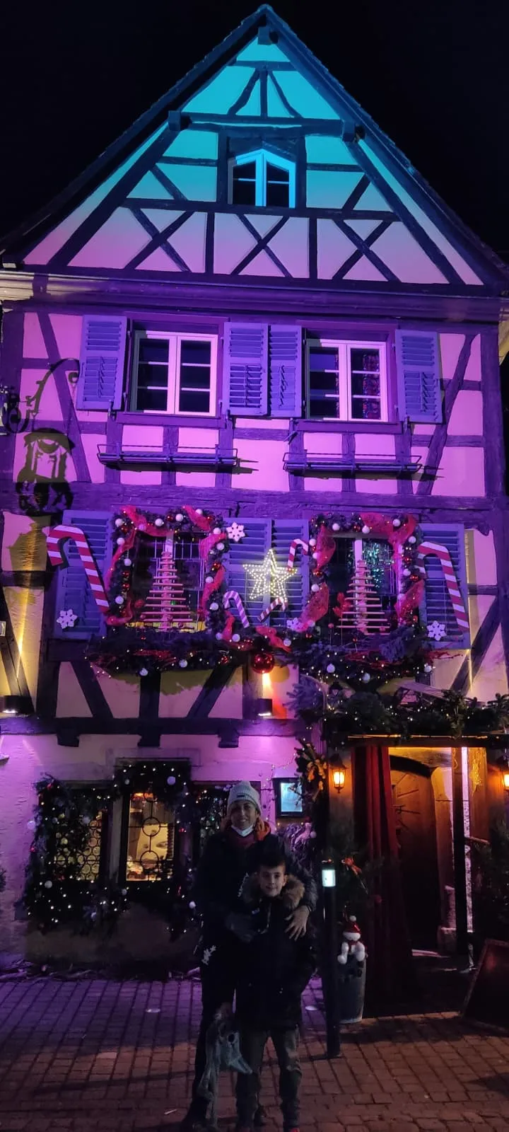 Fachada de entramado de madera iluminada y decorada por Navidad en Riquewihr, de noche