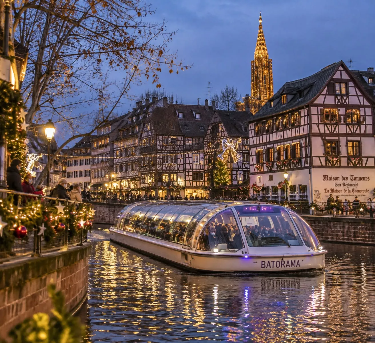 Barco turístico cubierto navegando por los canales de la Petite France, en Estrasburgo, al anochecer